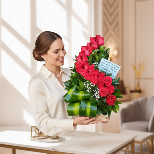 Mujer joven con blusa blanca sosteniendo un arreglo floral de rosas rojas en forma curva con hojas verdes y tarjeta, en una sala luminosa y elegante